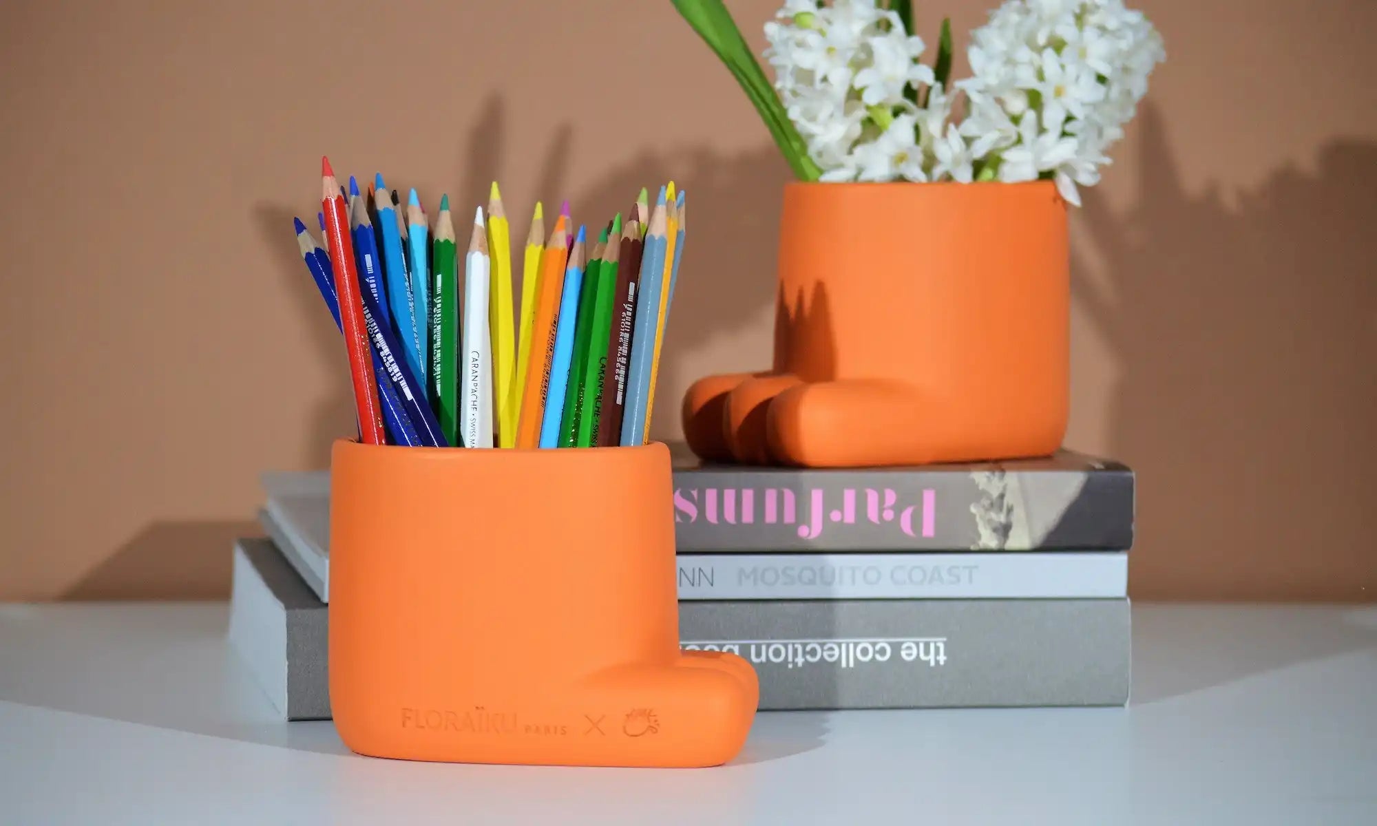 Orange ceramic or clay pot holding colorful pencils.