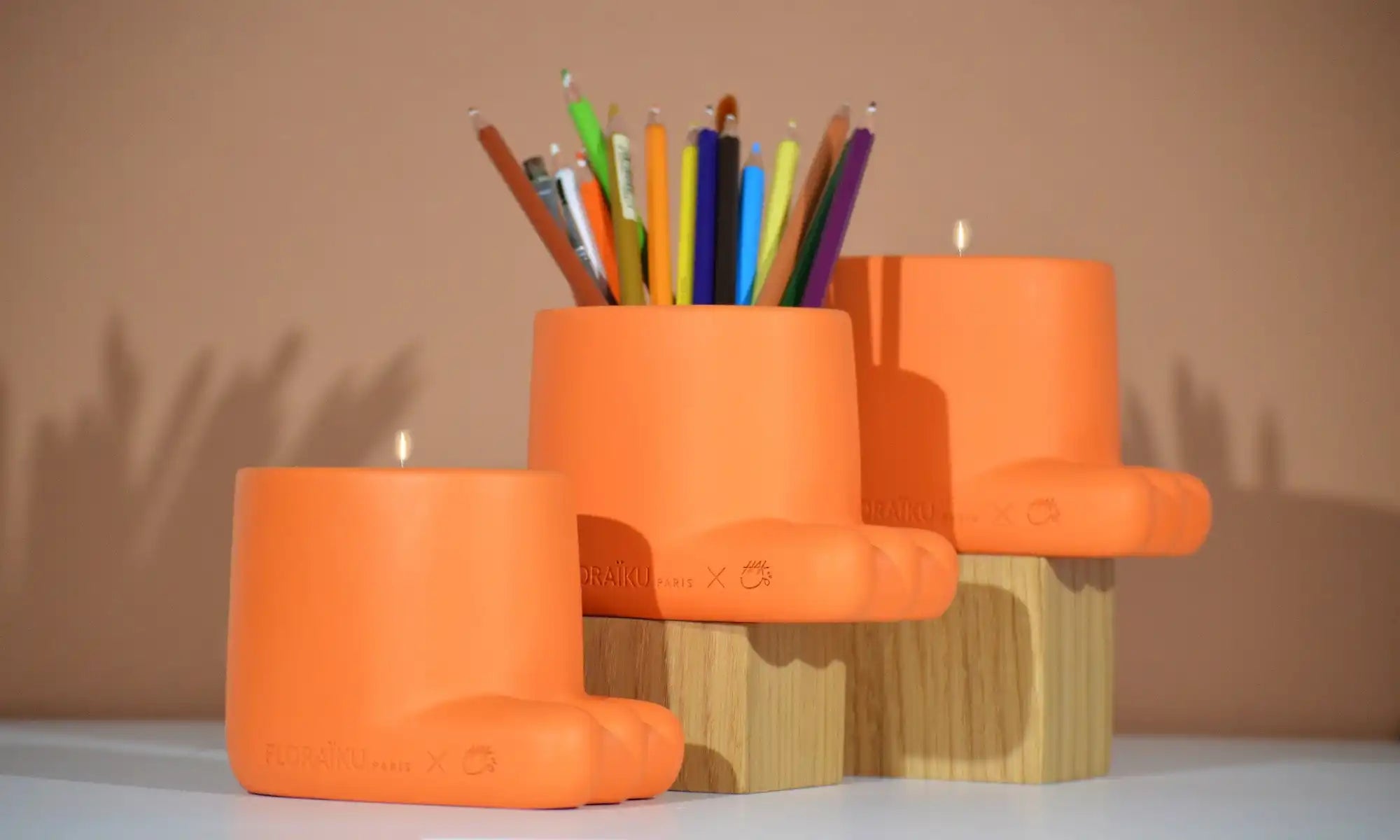 Orange ceramic or clay pots arranged in a stepped formation holding pencils and art supplies.